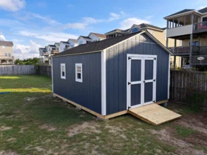 Spacious navy blue utility shed or backyard workshop with white trim, double doors, and two side-entry windows.