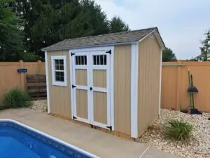 A swimming pool surrounded by a fence, with a shed visible nearby
