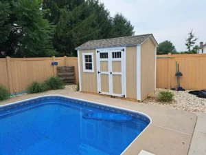 A swimming pool surrounded by a fence, with a shed visible nearby